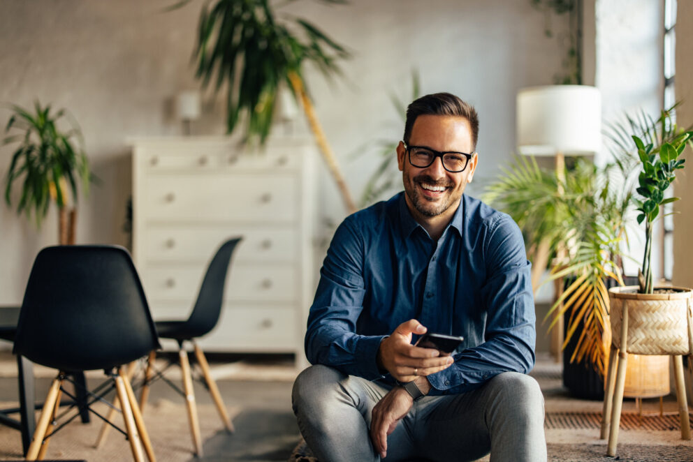 Portrait of a smiling businessman, looking at the camera, holdin